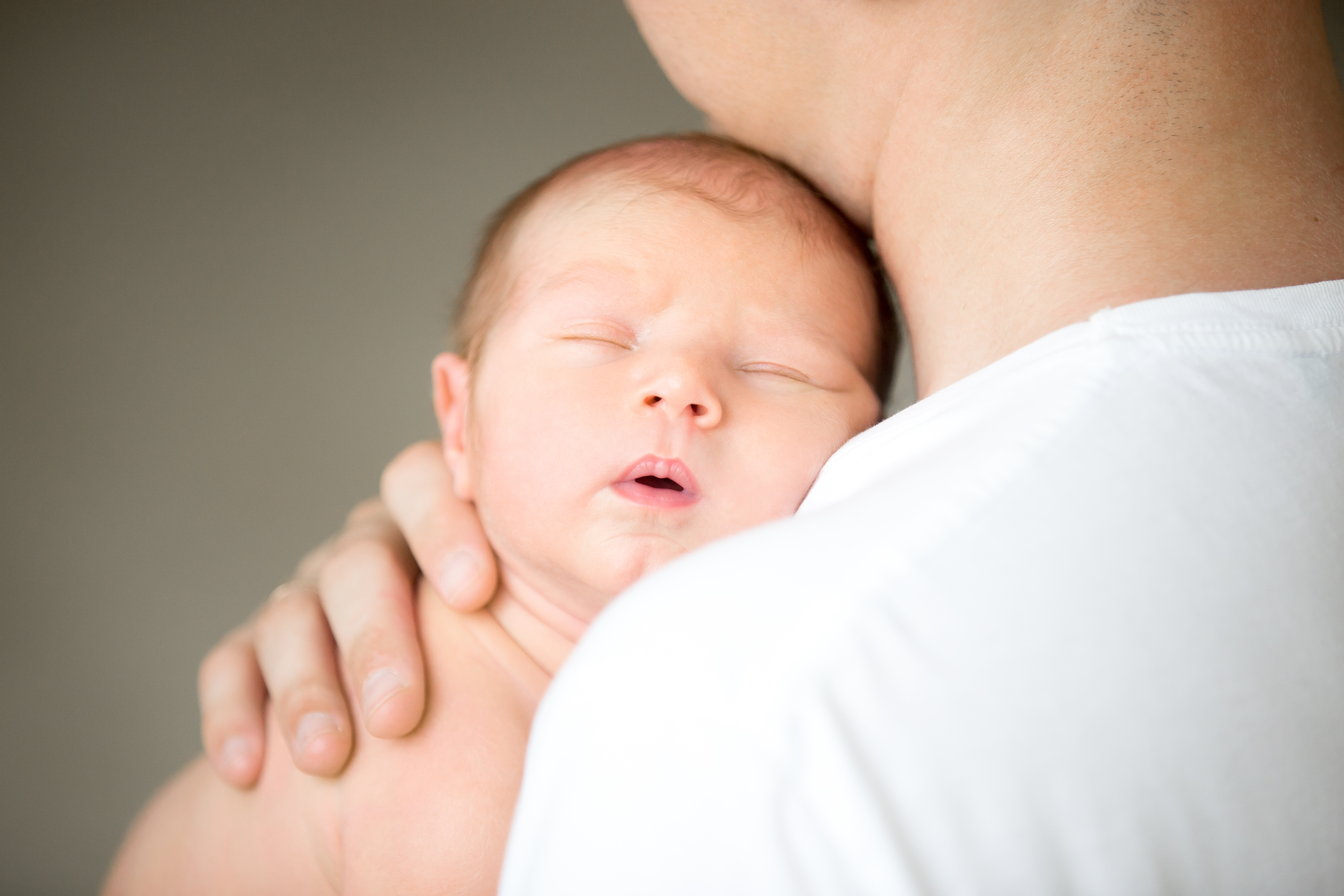 Sleeping newborn at the male shoulder Sleeping newborn at the male shoulder, hold gently by a hand. Family, healthy birth concept photo, close up
